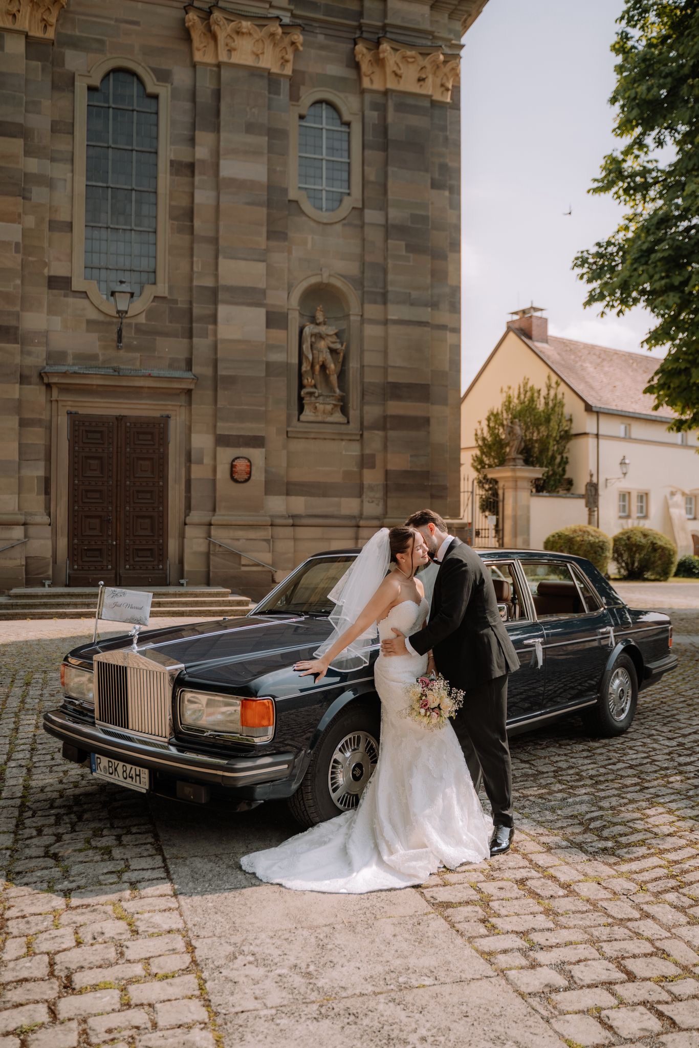 Brautpaar vor der Kirche, daneben der Rolls-Royce Silver Spur
