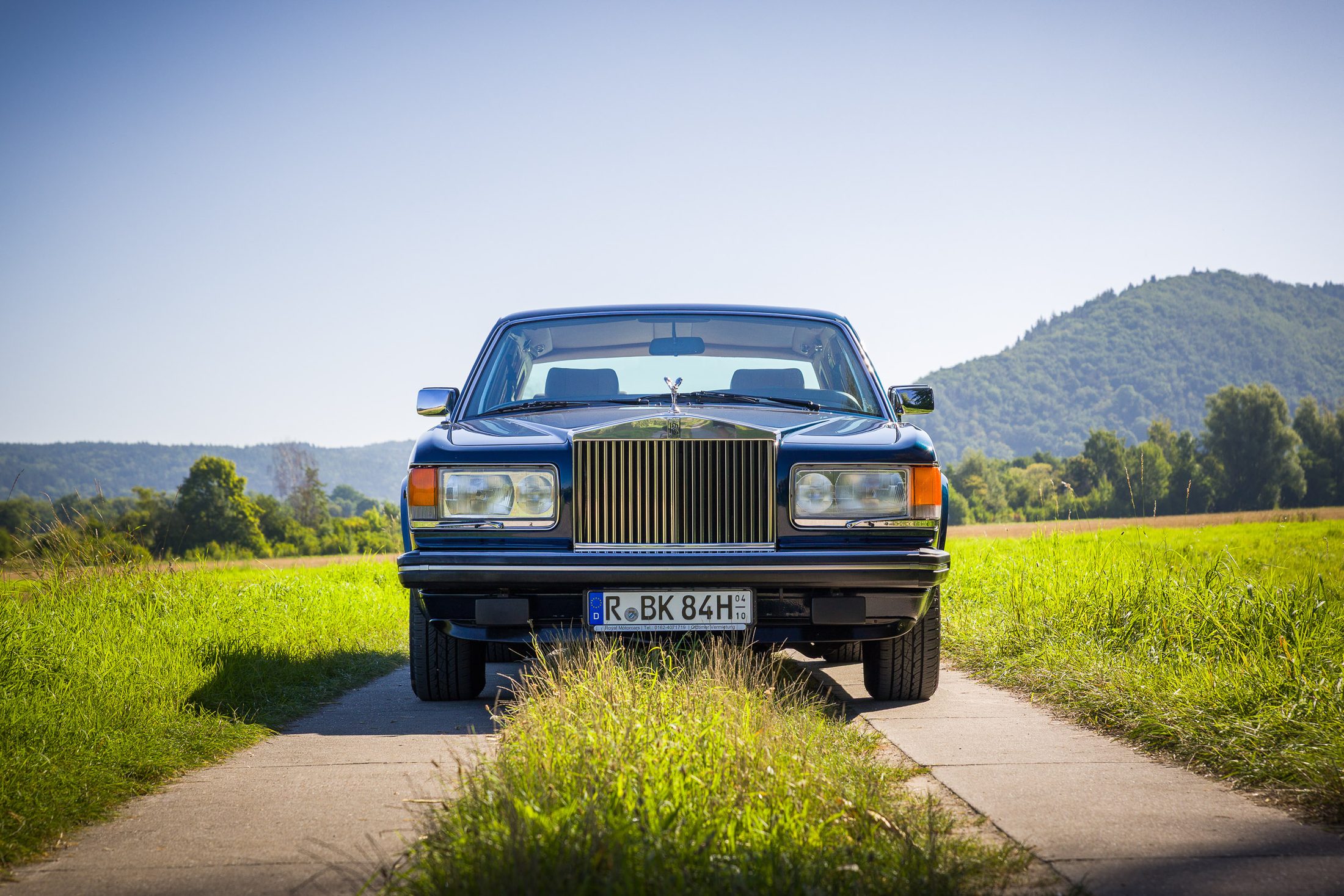 Rolls-Royce Silver Spur frontal auf einem Feldweg vor Hügeln