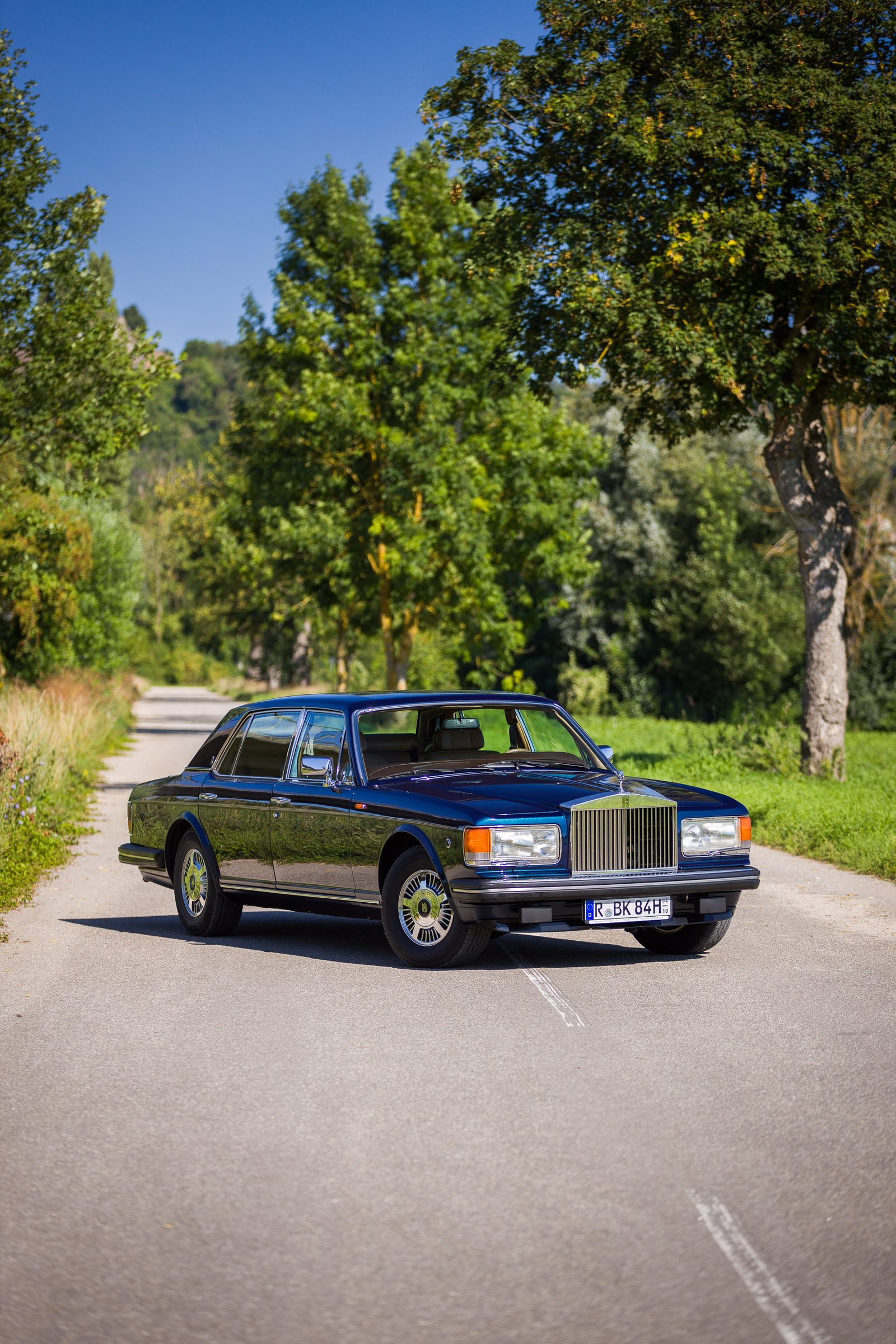 Rolls-Royce Silver Spur im Seitenprofil zwischen Bäumen